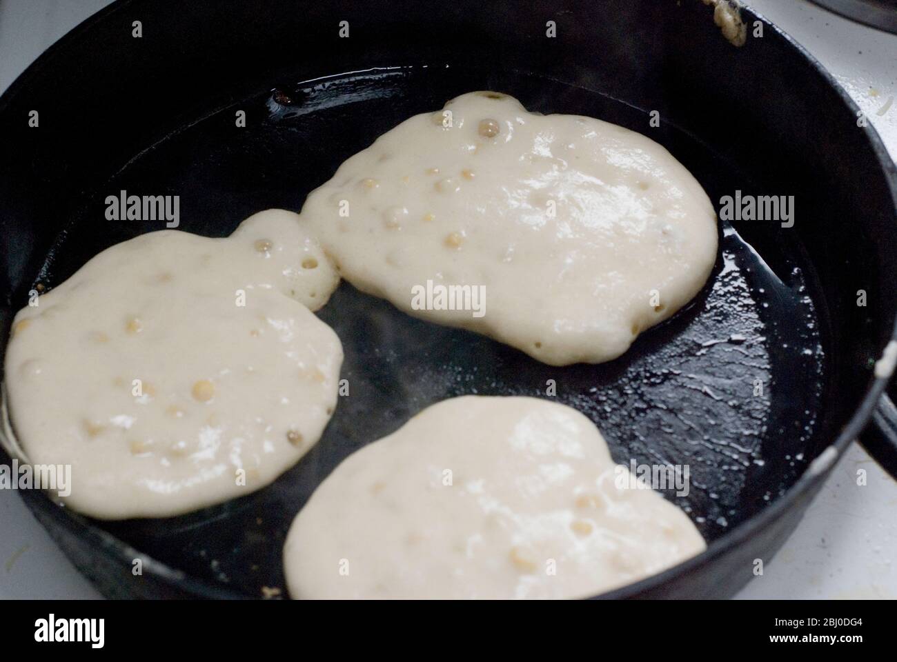 Cuisson des beignets de maïs dans une poêle en fonte épaisse. - Banque D'Images