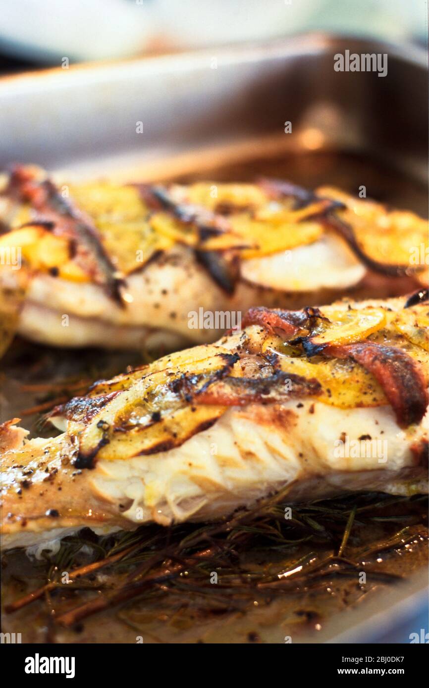 Filets de monkfish rôtis sur un lit de romarin avec citron et anchois - Banque D'Images