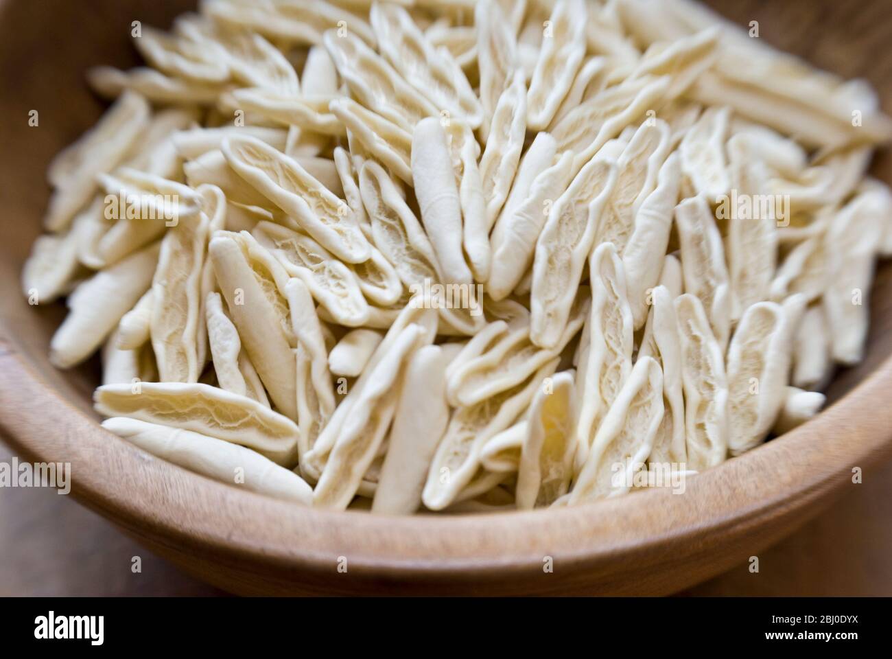 Formes de pâtes cigatelli brutes, dans un ancien bol en bois sur surface en bois - Banque D'Images