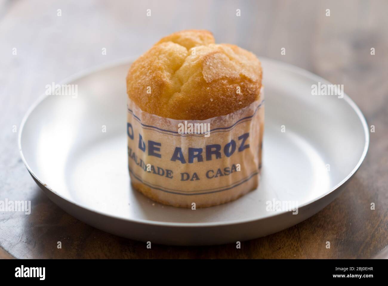 Gâteau de type muffin portugais classique fabriqué avec du riz dans un emballage en papier sur une plaque métallique, avec une tasse de café noir - Banque D'Images