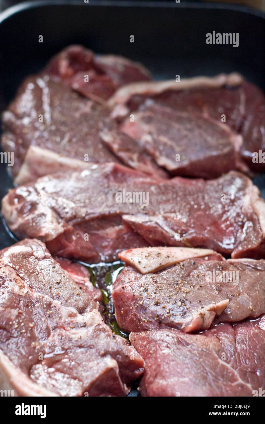 Morceaux de steak de croupe marinés à l'huile d'olive, au vin rouge et au poivre noir - Banque D'Images