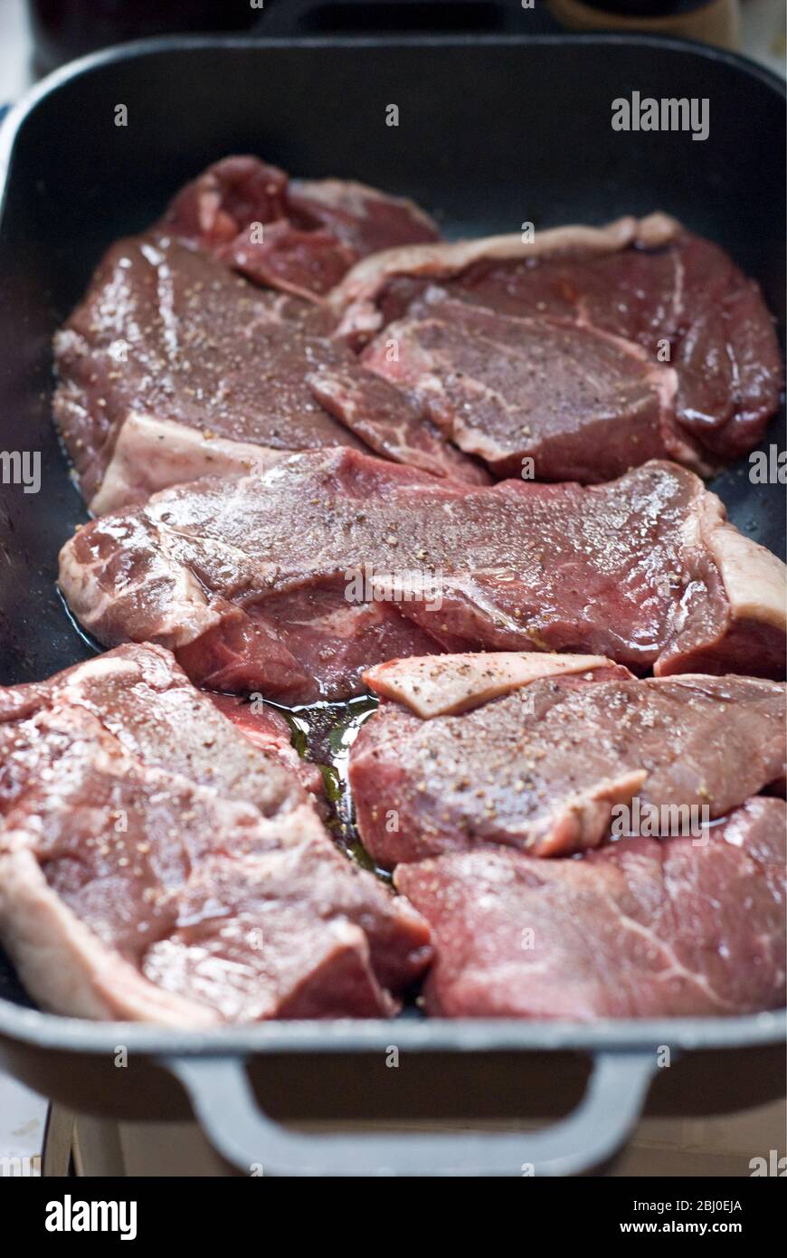 Morceaux de steak de croupe marinés à l'huile d'olive, au vin rouge et au poivre noir - Banque D'Images