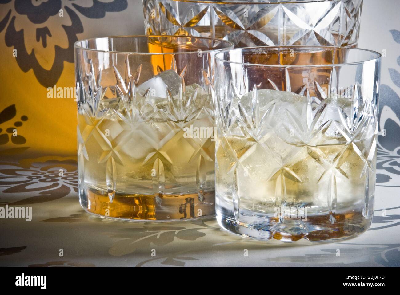 Whisky écossais sur glace dans des verres en cristal de plomb coupés sur une surface argentée décorative, avec décanteur. - Banque D'Images