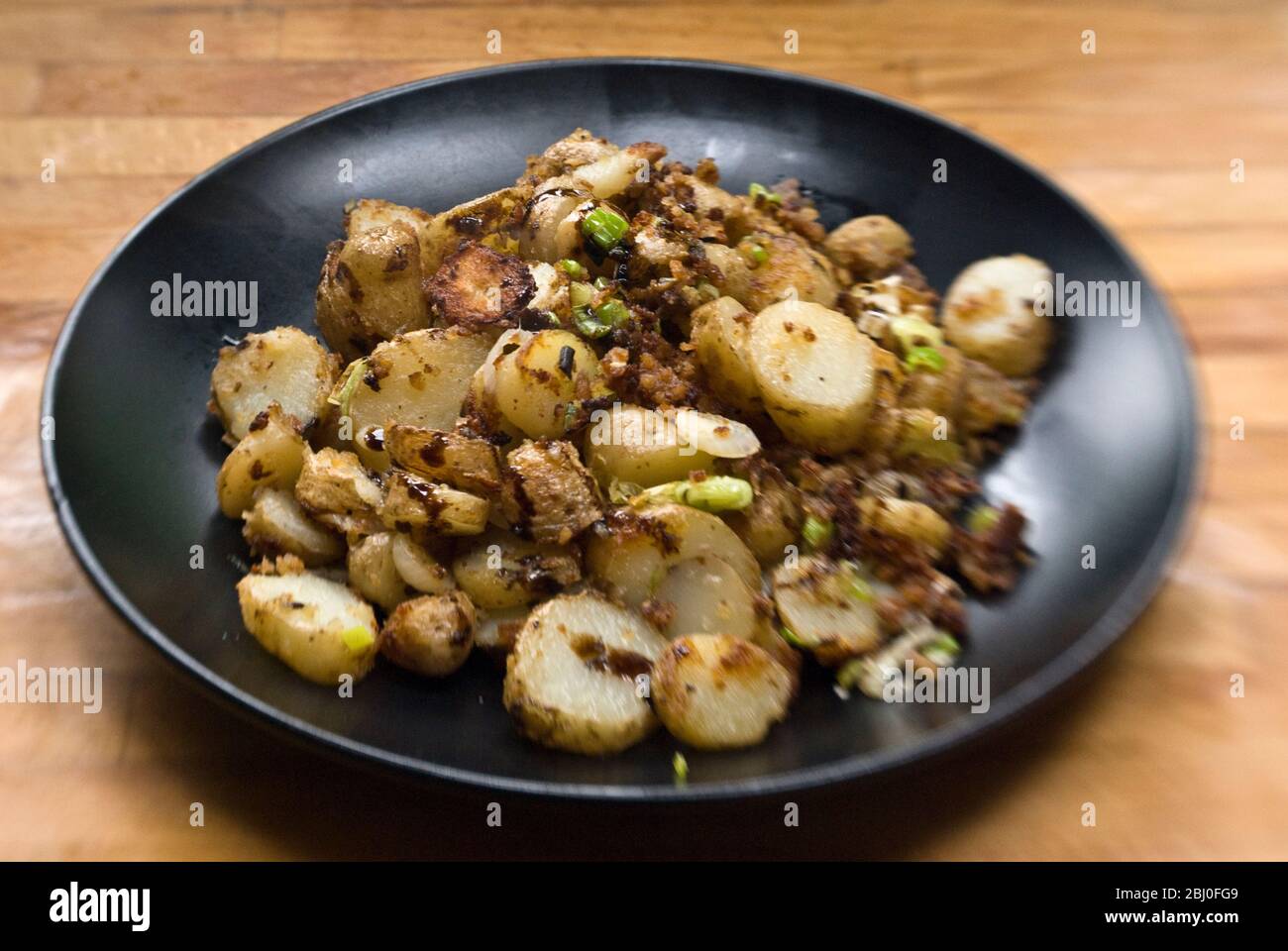 Plat de pommes de terre frites, sautées avec anchois, oignons de printemps et chapelure. - Banque D'Images
