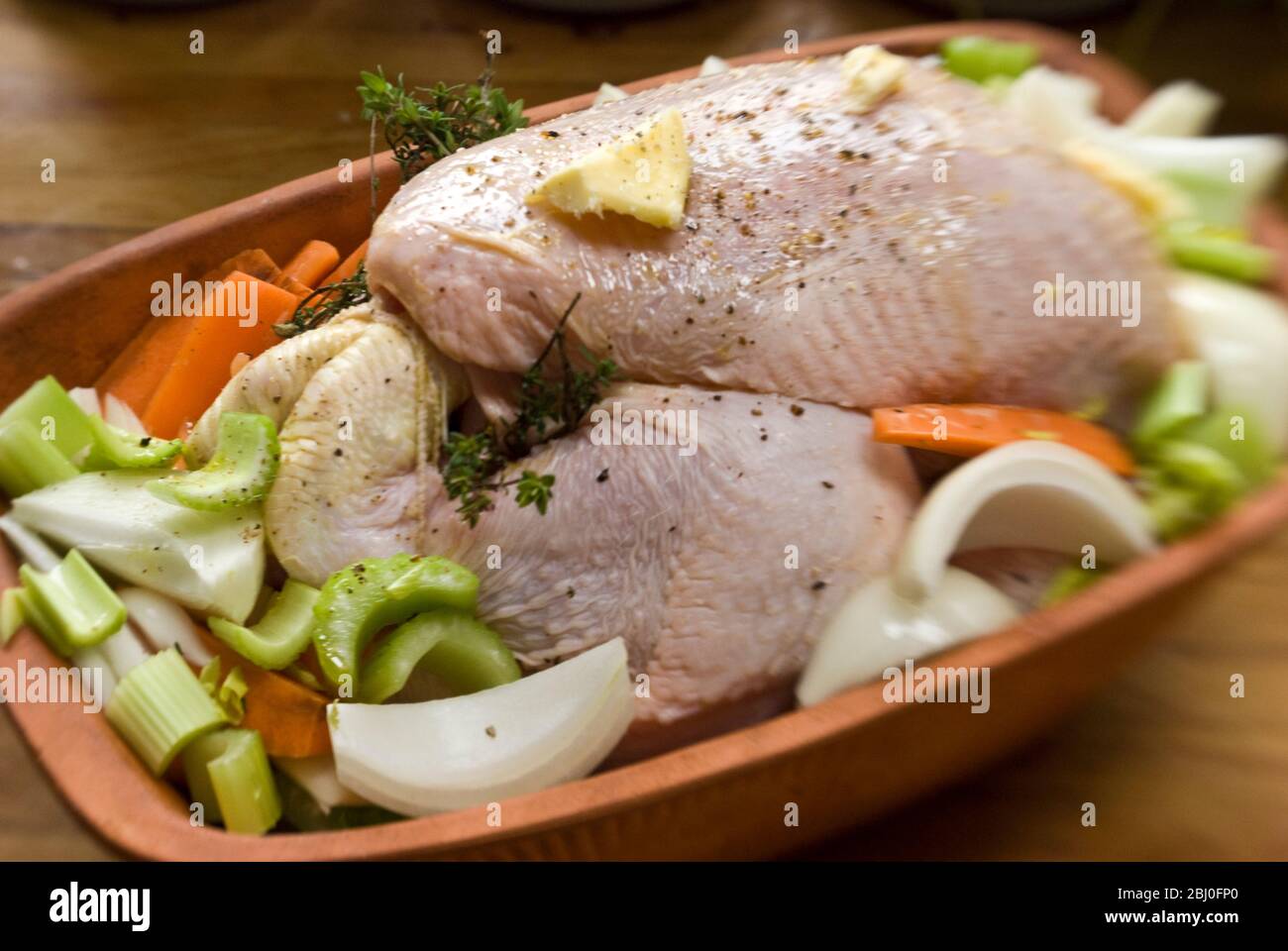 Poulet préparé pour le four dans une brique de poulet en terre cuite avec oignons, céleri, carottes, thym, et un peu de vin blanc - Banque D'Images Poulet préparé pour le four dans une brique de poulet en terre cuite avec oignons, céleri, carottes, thym, et un peu de vin blanc - Banque D'Images