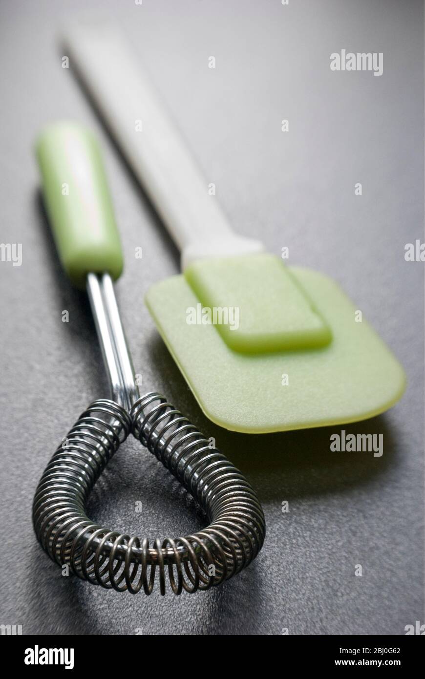 Equipement de cuisine, fouet métallique et spatule verte en plastique et silicone - Banque D'Images