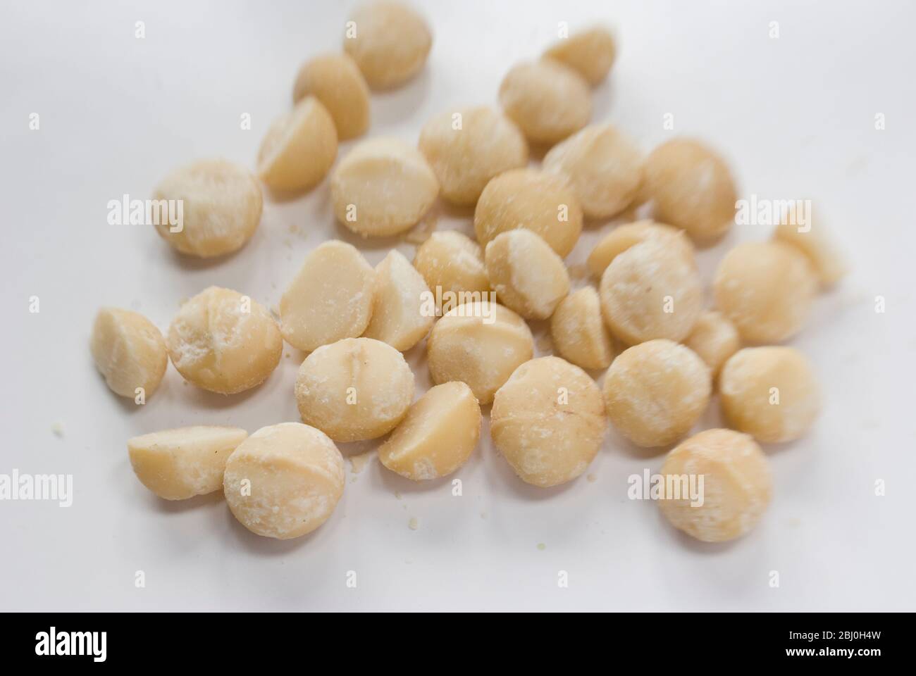 Noix de macadamia rôties sèches décortiquées, sur surface blanche - Banque D'Images