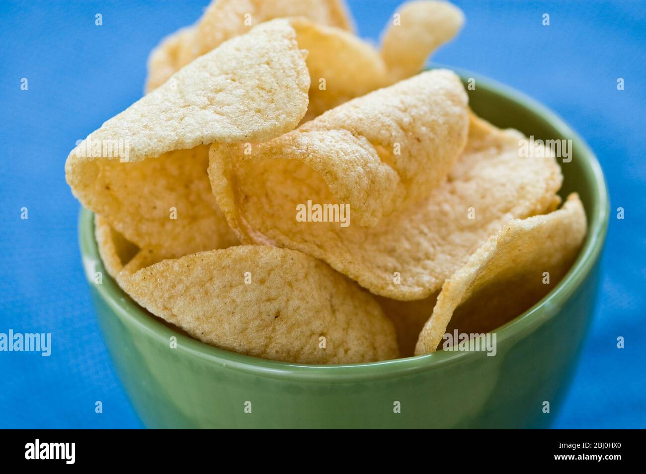 Craquelins de crevettes thaïlandais dans un bol de poterie verte sur un tissu bleu - Banque D'Images