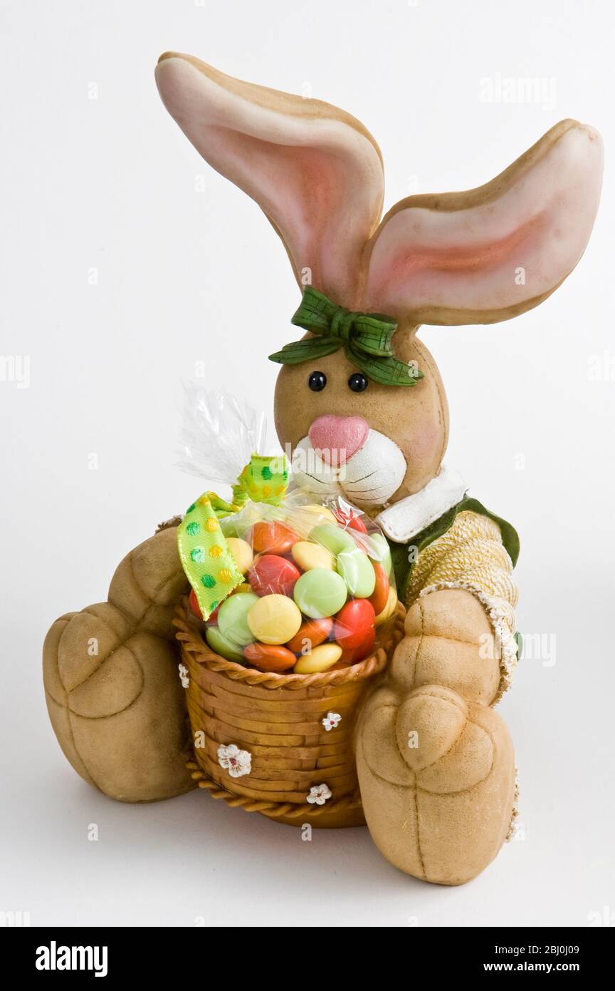Joli ornement de lapin avec panier de bonbons comme cadeau de Pâques. - Banque D'Images