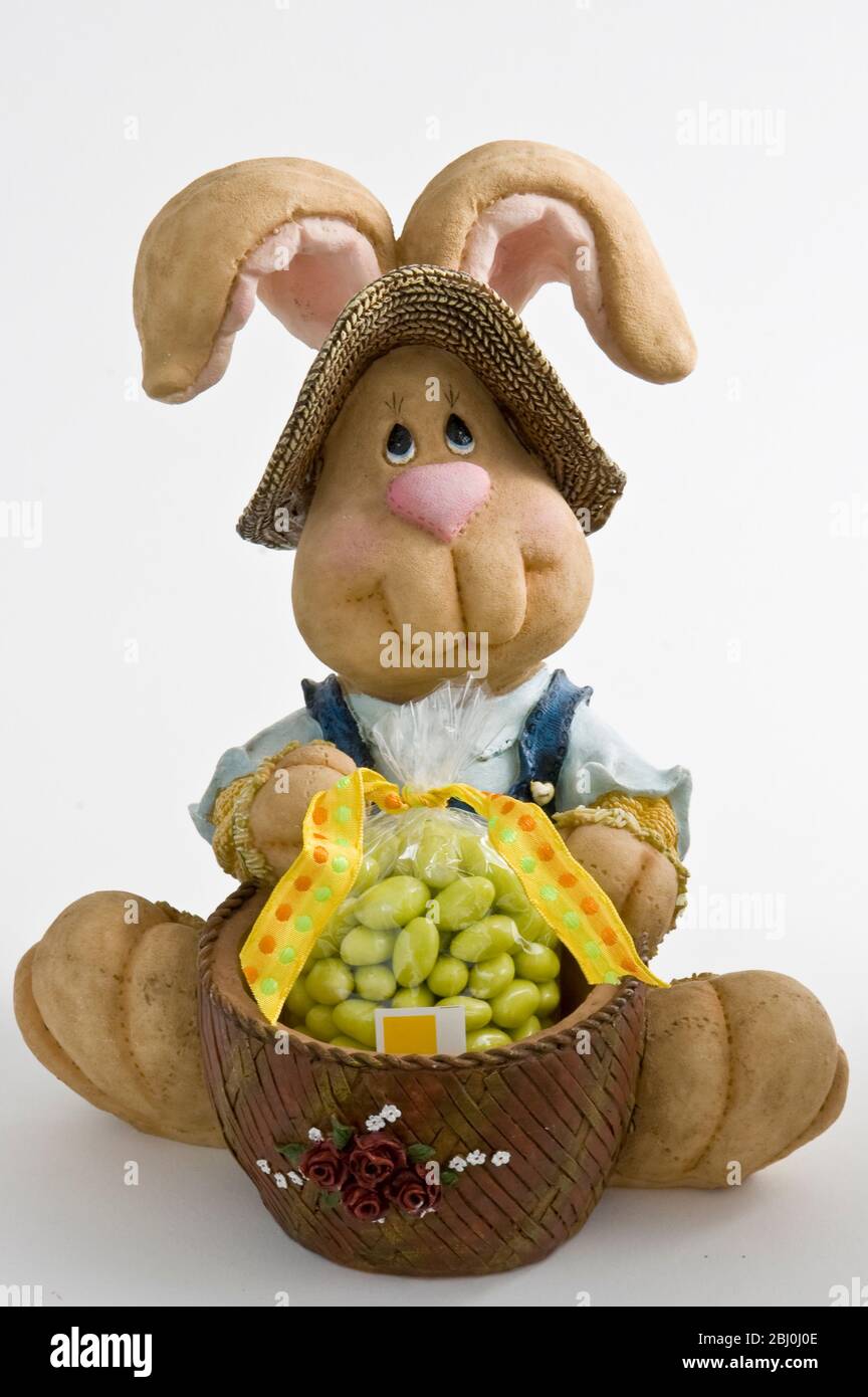 Joli ornement de lapin avec panier de bonbons comme cadeau de Pâques. - Banque D'Images