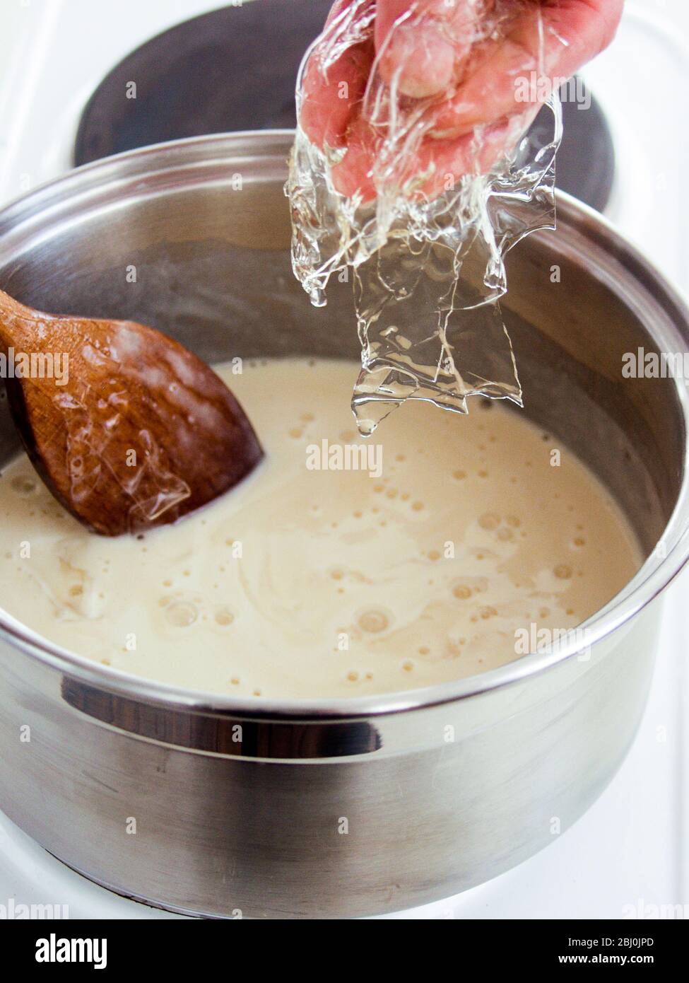 Ajouter des feuilles de gélatine ramollies à la crème anglaise pour épaissir et régler - Banque D'Images