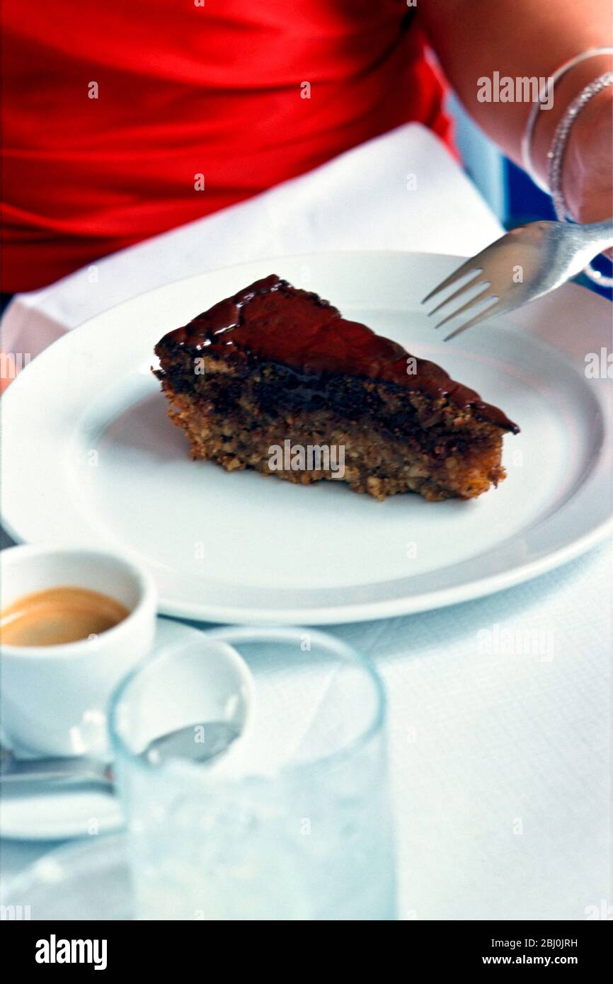 Chocolat torte sur la plaque blanche dans le restaurant avec fille en robe rouge - Banque D'Images