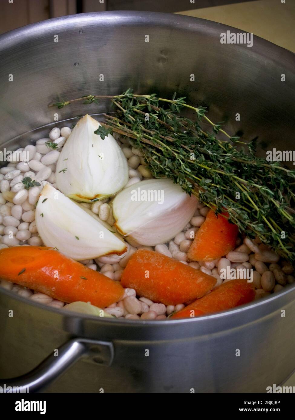 Les ingrédients pour une soupe de haricots blancs dans une casserole en acier inoxydable - Banque D'Images