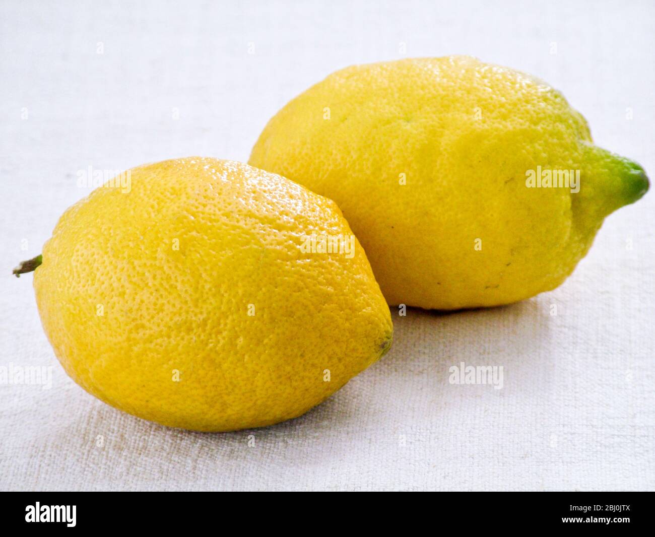 Deux citrons entiers sur fond de toile de lin blanc - Banque D'Images
