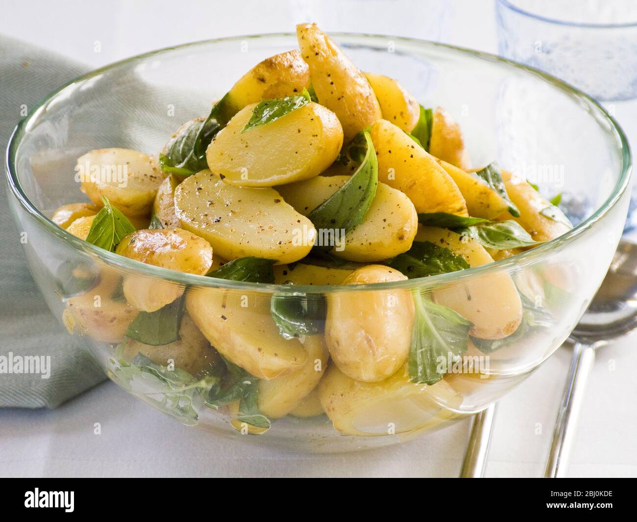 Nouvelle salade de pommes de terre dans la vinaigrette à l'huile d'olive, au vinaigre de vin et à la moutarde complète , avec feuilles de basilic - Banque D'Images