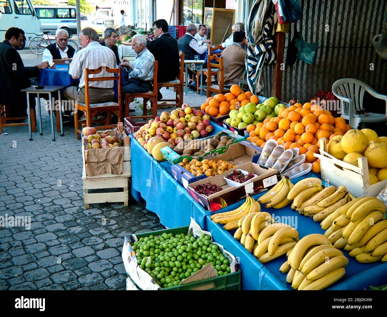 Fruits staller à l'extérieur du magasin avec des hommes jouant au jeu et boire du café en arrière-plan. Dalyan, Anatolie, Turquie - Banque D'Images