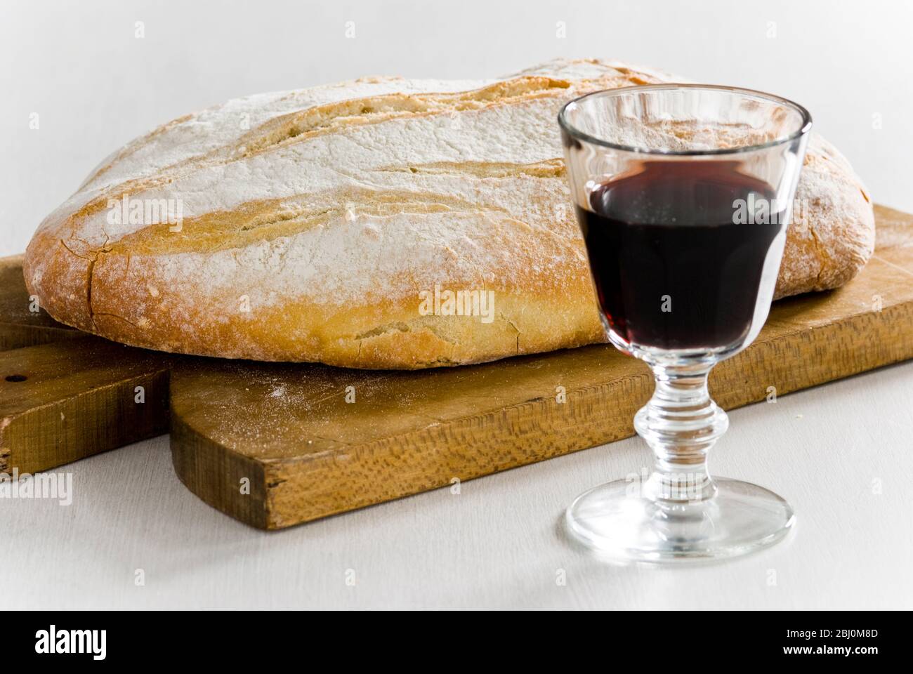 Verre de vin rouge avec pain blanc rustique croustillant sur planche en bois - Banque D'Images
