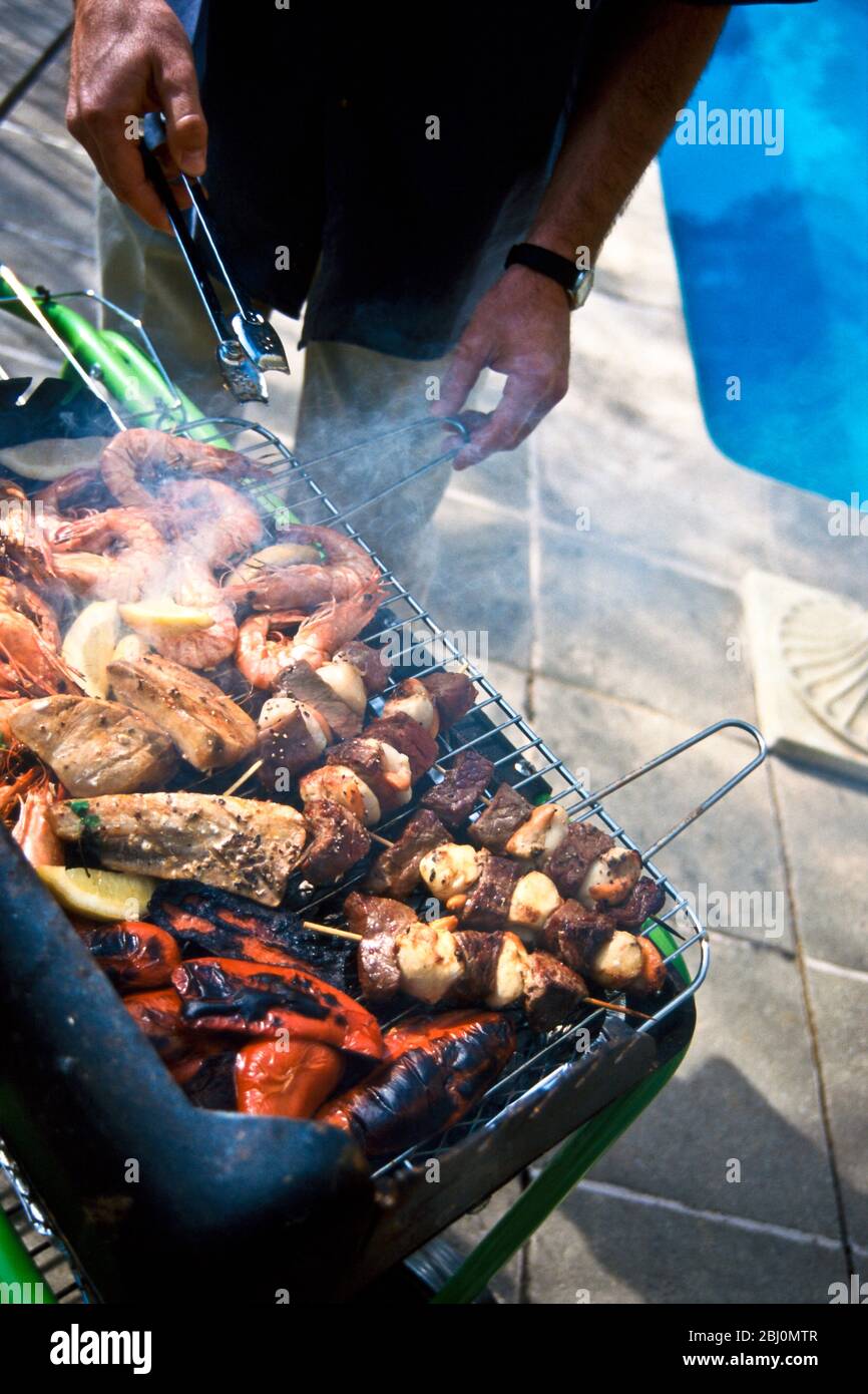 Griller des pétoncles et des steaks, des poivrons rouges, des crevettes méditerranéennes et des steaks de thon sur un barbecue au charbon de bois - Banque D'Images