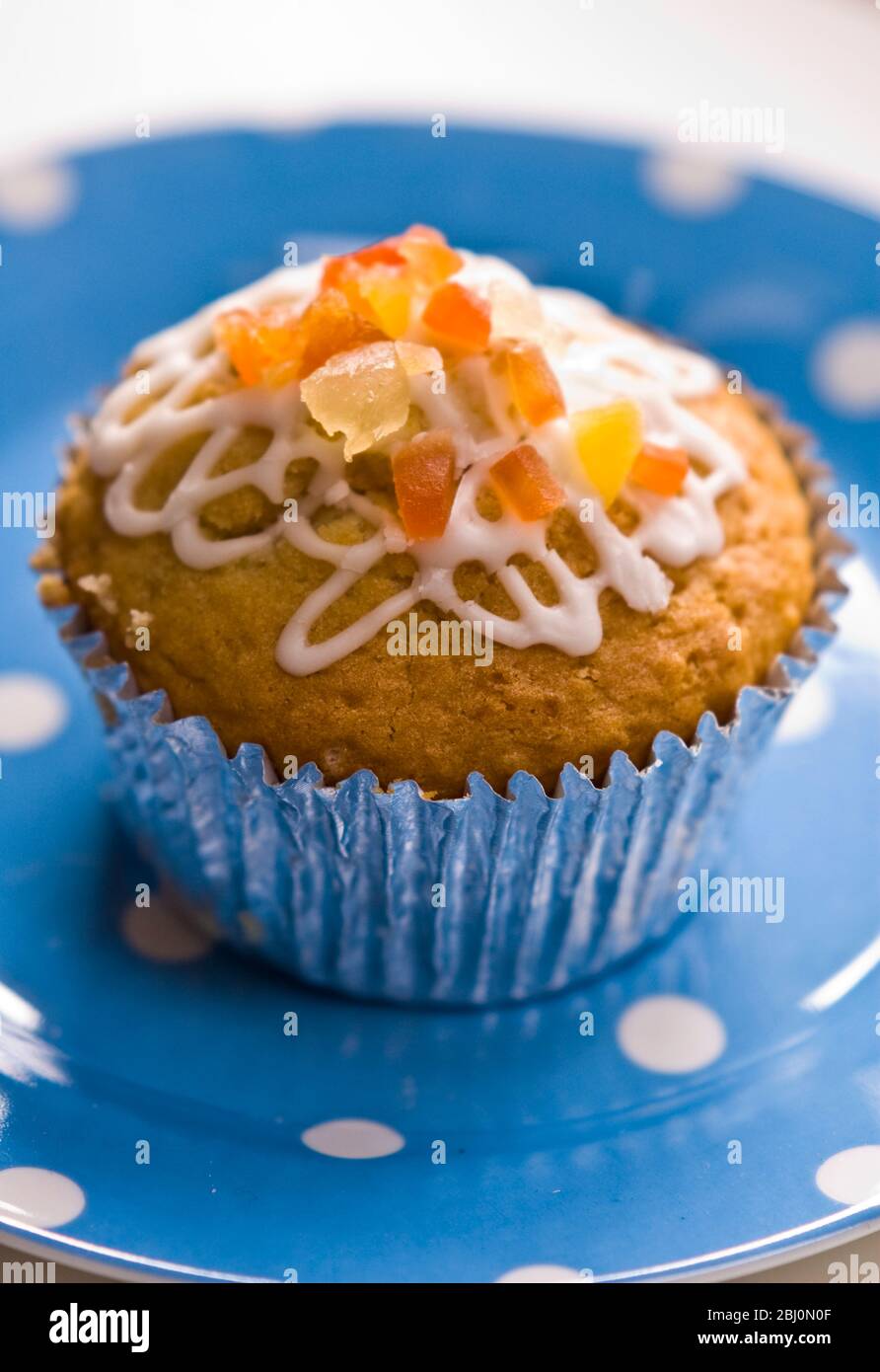 Muffin décoré de glaçage coucheté et de pelure confite sur la plaque bleue à pois - Banque D'Images