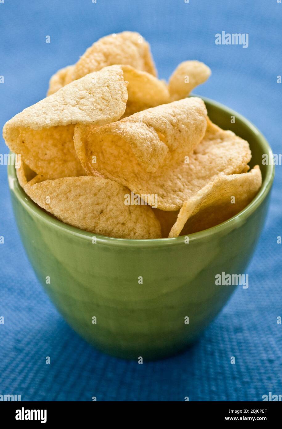 Craquelins de crevettes thaïlandais dans un bol de poterie verte sur un tissu bleu - Banque D'Images