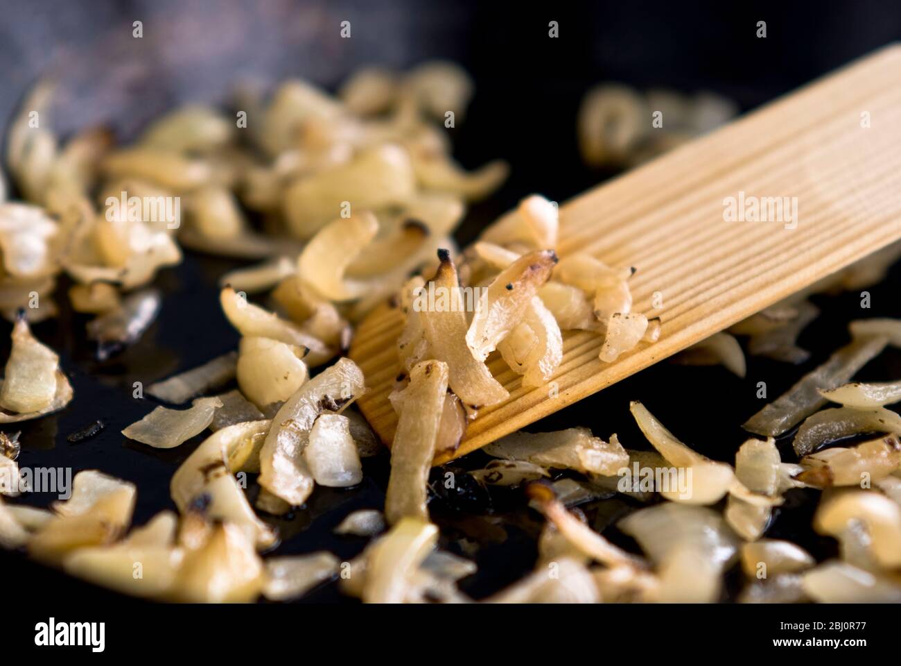 Friture d'oignons hachés dans une poêle noire anti-adhésive - Banque D'Images