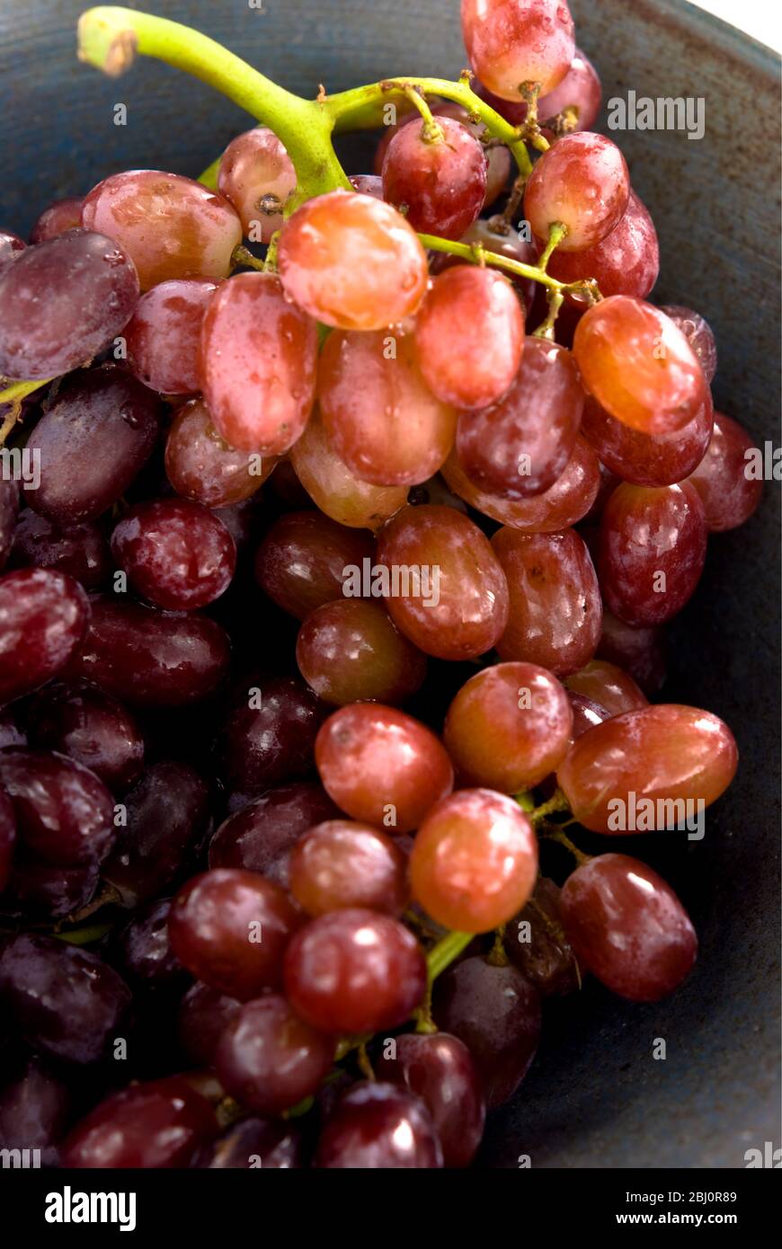 Bouquet de raisins rouges sans semis sur plaque noire - Banque D'Images
