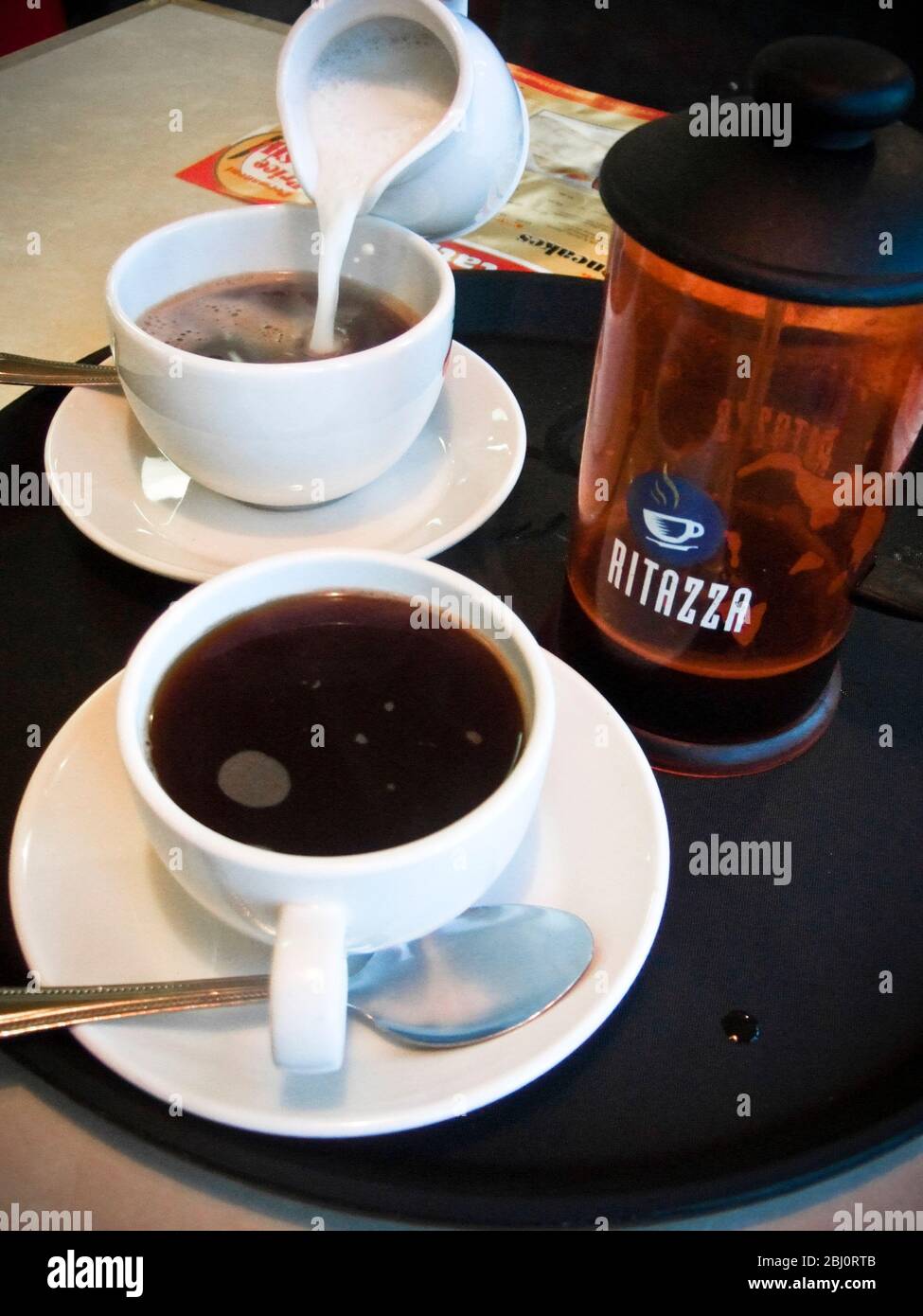 Verser du lait dans une tasse de café à la cafétéria du restaurant Little Chef, Dumfries, Écosse - Banque D'Images