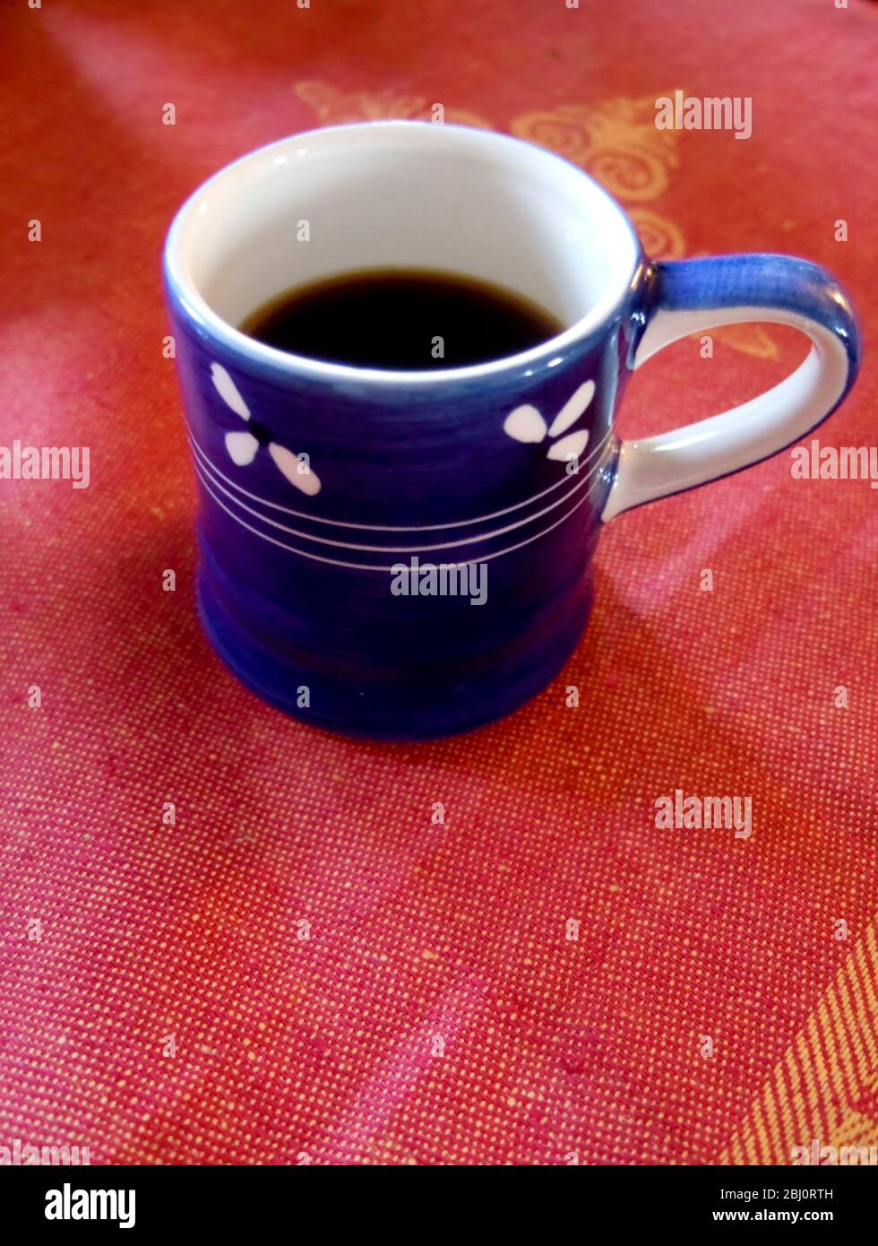 Joli mug bleu de café noir dans une nappe en tissu sari - Banque D'Images