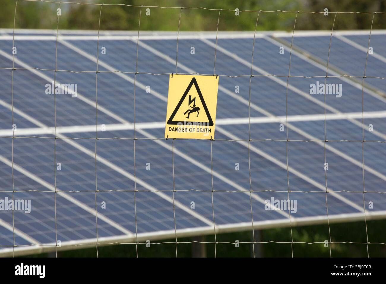 Un panneau d'avertissement à côté d'une ferme solaire indiquant un danger d'électrocution et de mort. North Dorset Angleterre Royaume-Uni GB Banque D'Images