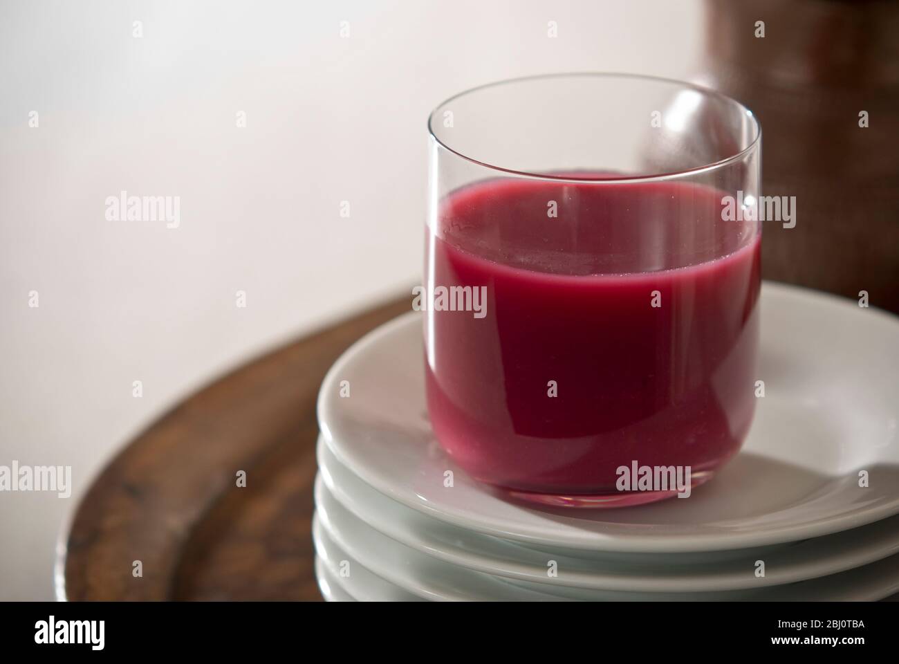 Jus de grenade en verre transparent sur pile de plaques blanches - Banque D'Images