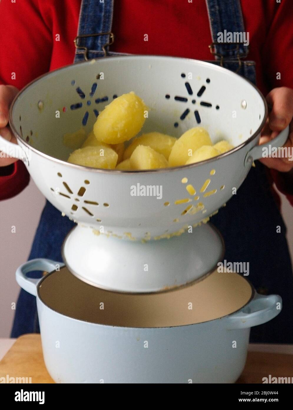 Les pommes de terre bouillies sont secouées dans la passoire pour sécher complètement et pour casser légèrement la surface avant de mettre au four avec de l'huile ou de la graisse pour faire du perf Banque D'Images