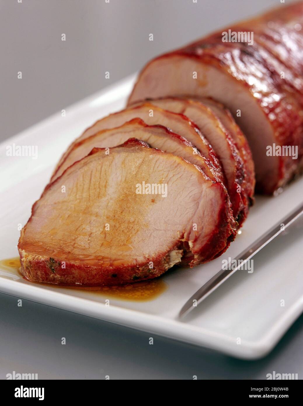 Filet de porc rôti sur plaque blanche - Banque D'Images