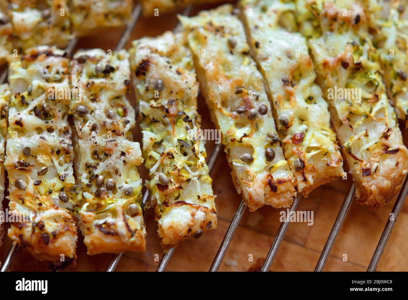 Les pailles de fromage fraîchement cuites refroidissent sur le rack, faites avec une courgette râpée et des paillettes emmentales râpées sur une feuille de pâte feuilletée et arrosées de graines de chanvre Banque D'Images