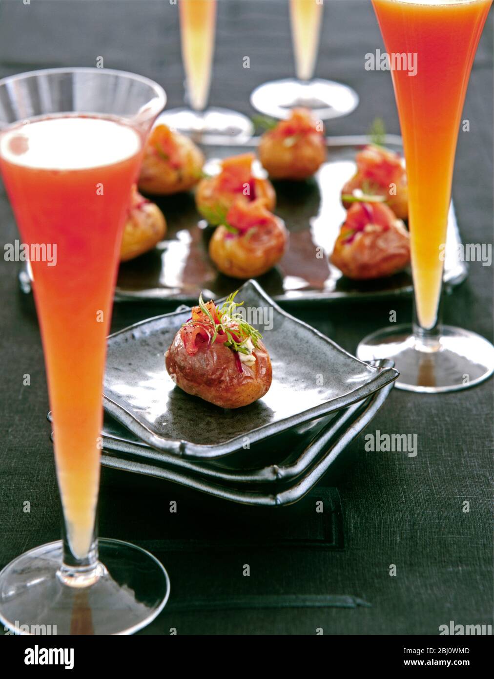Canapés intelligents de petites pommes de terre farcis avec crème aigre et aneth de saumon fumé, servis avec des cocktails lumineux dans de grands verres - Banque D'Images