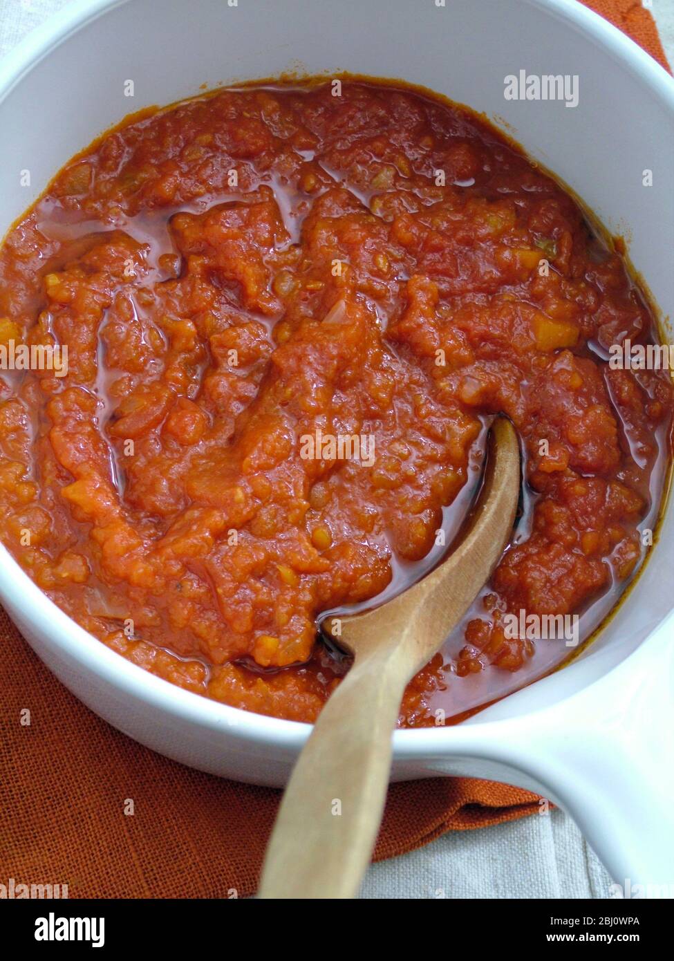 Sauce tomate maison fraîche dans une casserole en céramique blanche avec cuillère en bois - Banque D'Images