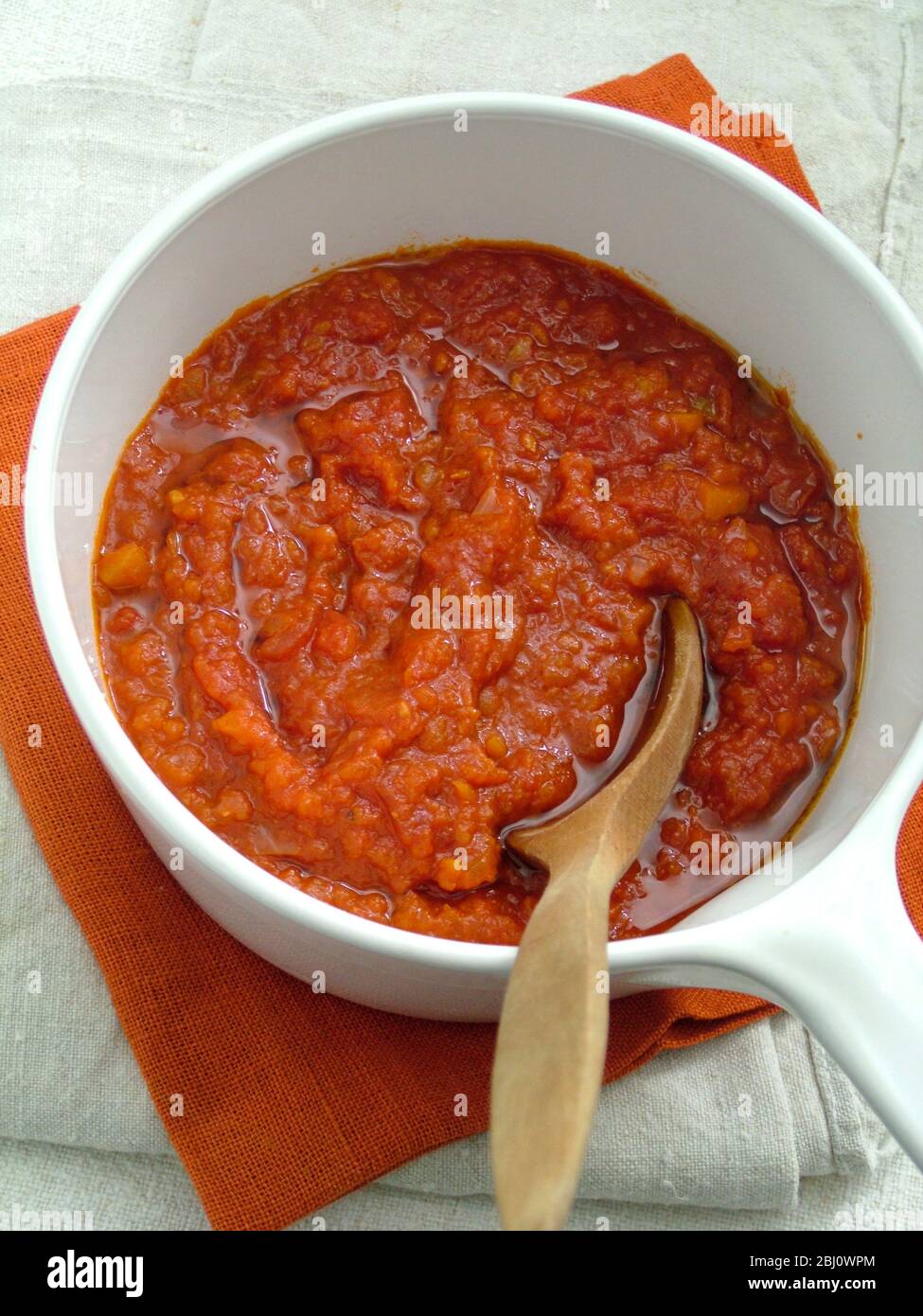 Sauce tomate maison fraîche dans une casserole blanche avec cuillère en bois - Banque D'Images