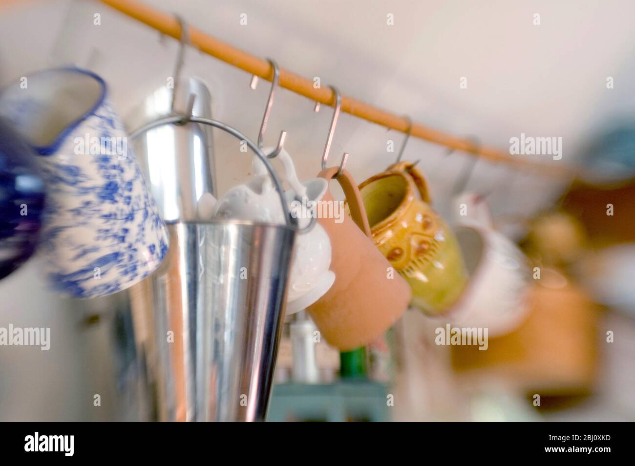 Collection de tasses en céramique accrochées au poteau dans la cuisine. Prise de vue avec objectif pour bébés en groupes - Banque D'Images