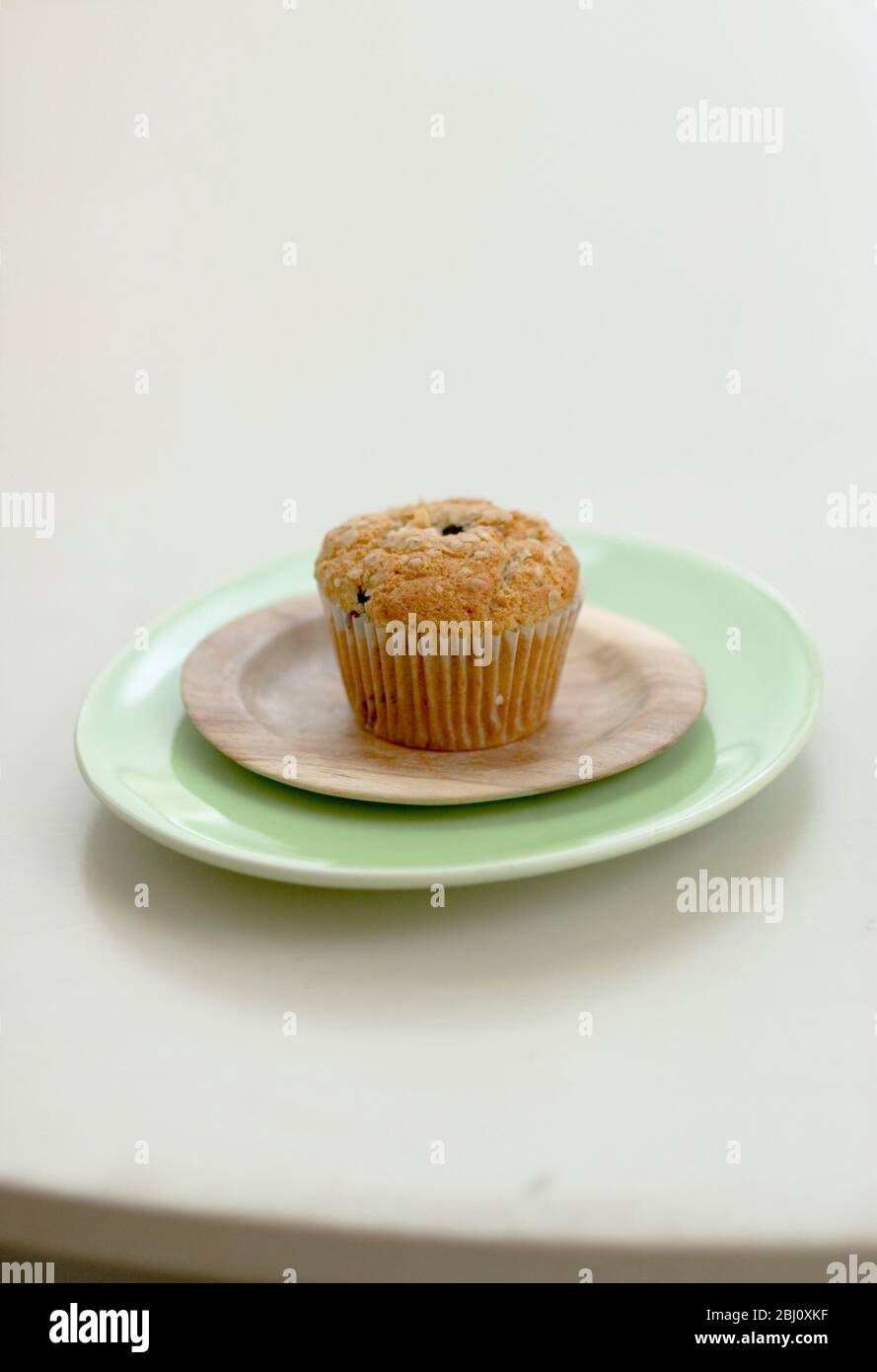 Muffin de son et de raisin sur une petite plaque en bois sur un plateau vert - Banque D'Images