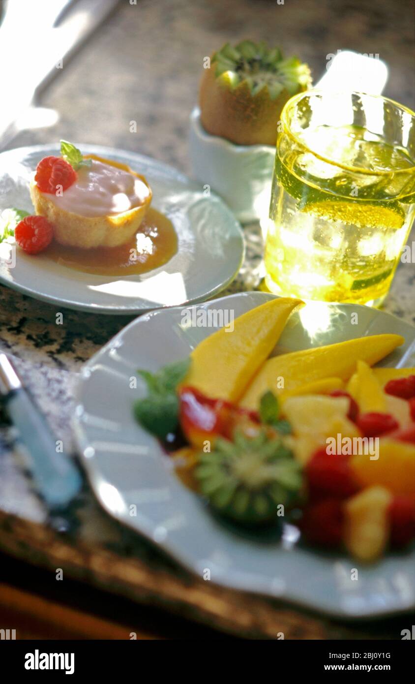 Desserts d'été - assiette de fruits et mousse aux fraises dans une vitrine à pâtisserie et kiwi vandqué dans une tasse d'égolat - Banque D'Images