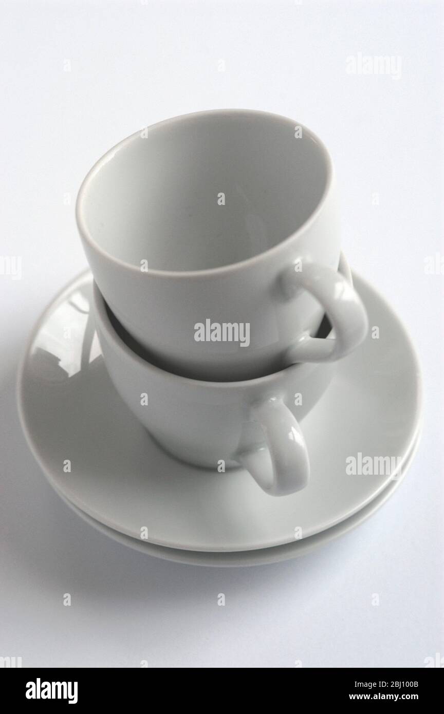 Deux tasses à café et soucoupes blanches empilées sur une surface blanche - Banque D'Images