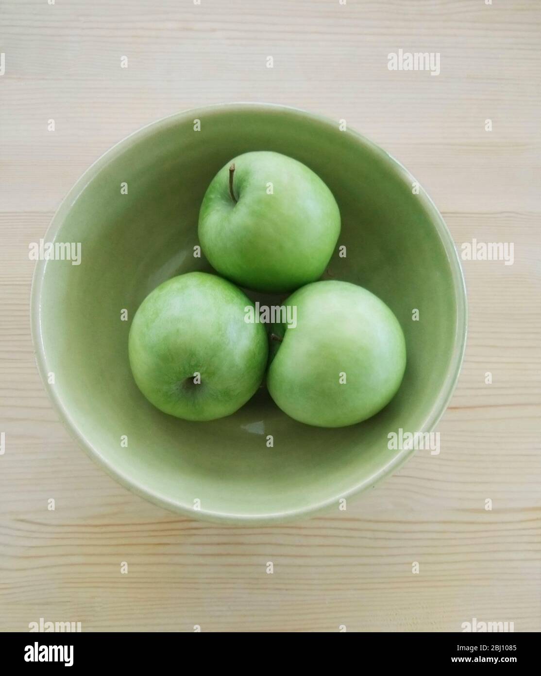 Trois pommes vertes Granny Smith dans un bol en poterie verte Banque D'Images
