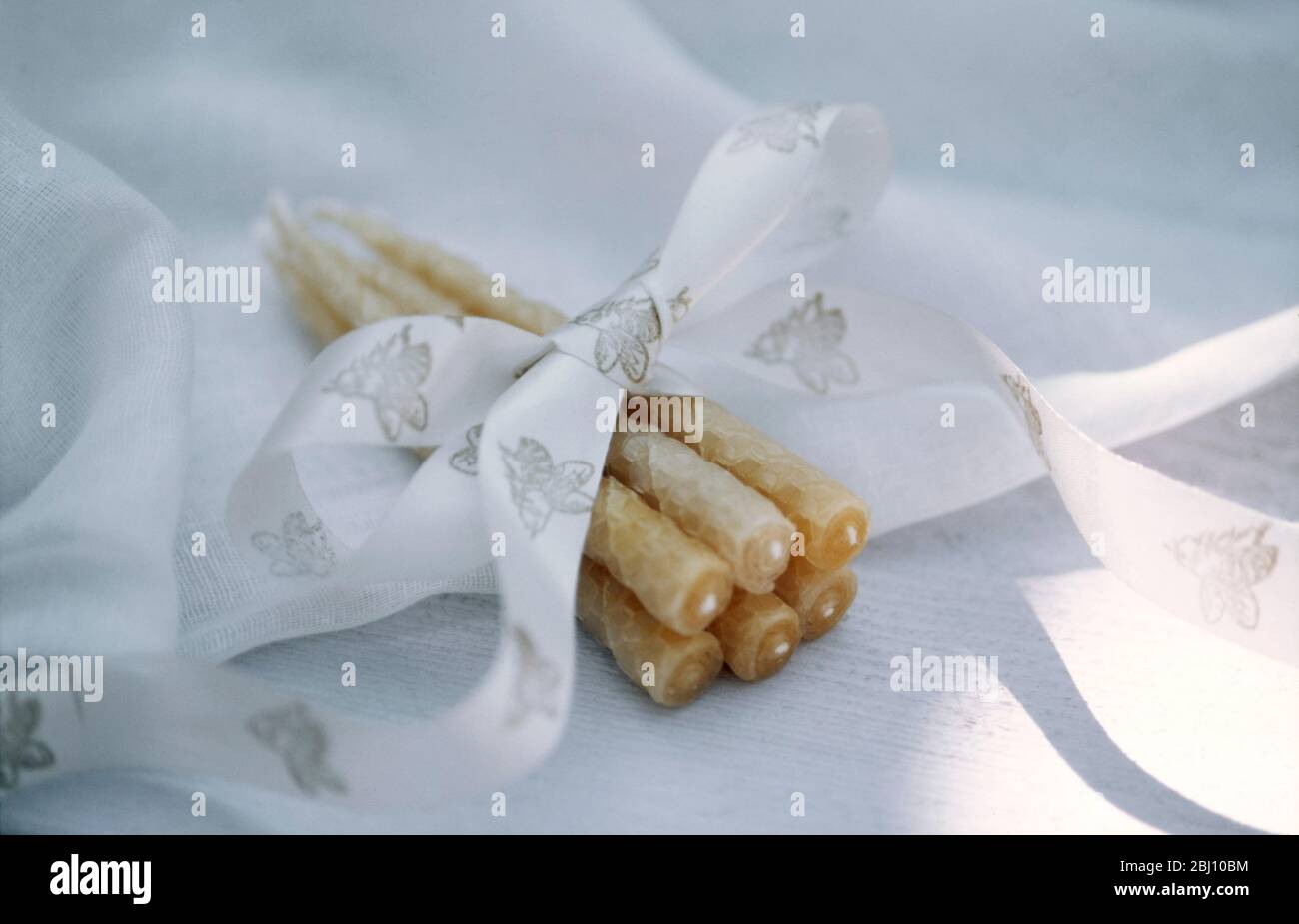 Paquet de bougies de cire d'abeille enveloppées dans un ruban à imprimé abeilles - Banque D'Images