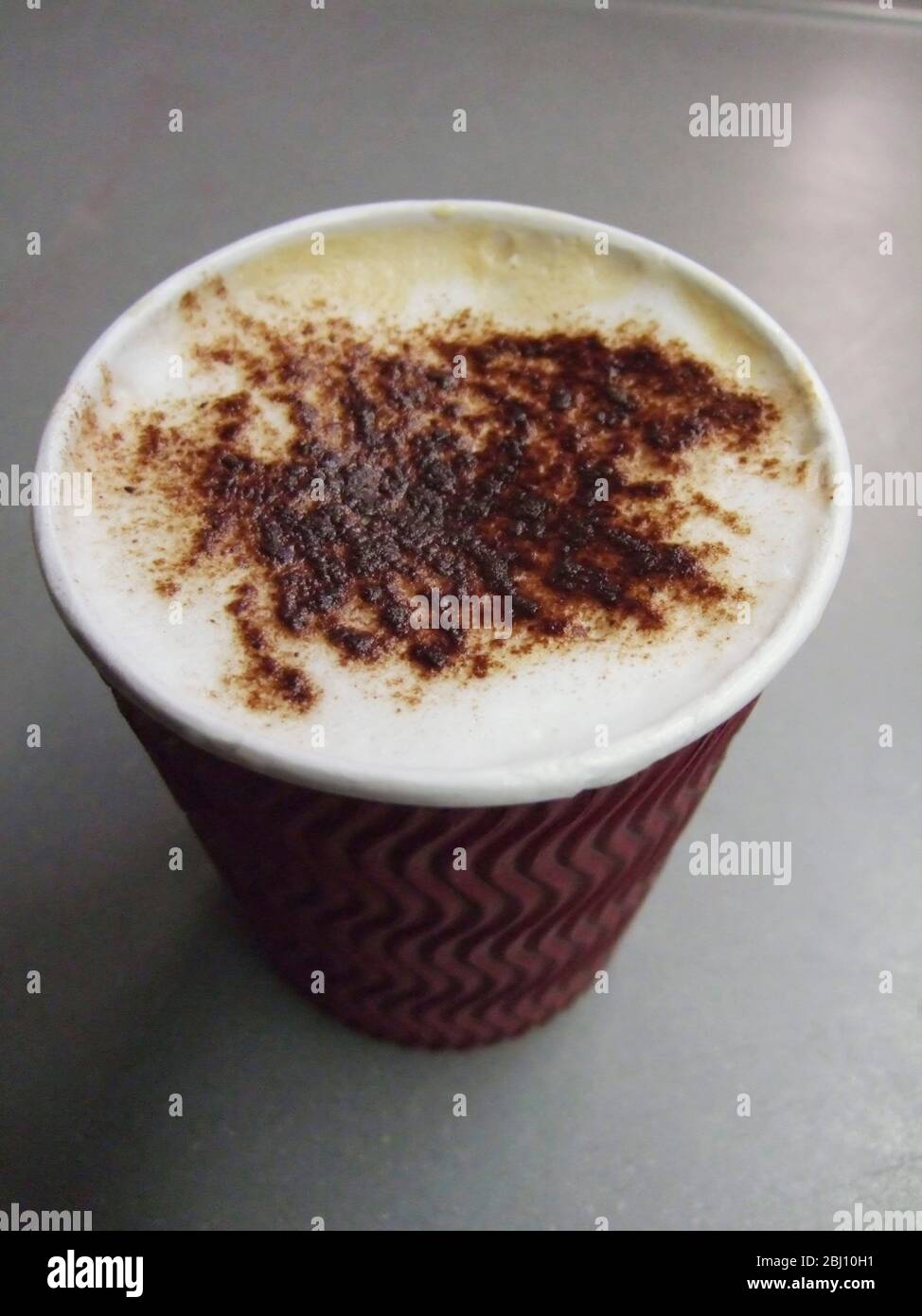 Tasse en carton de café de cappuccino acheté à la station café à boire en train - Banque D'Images