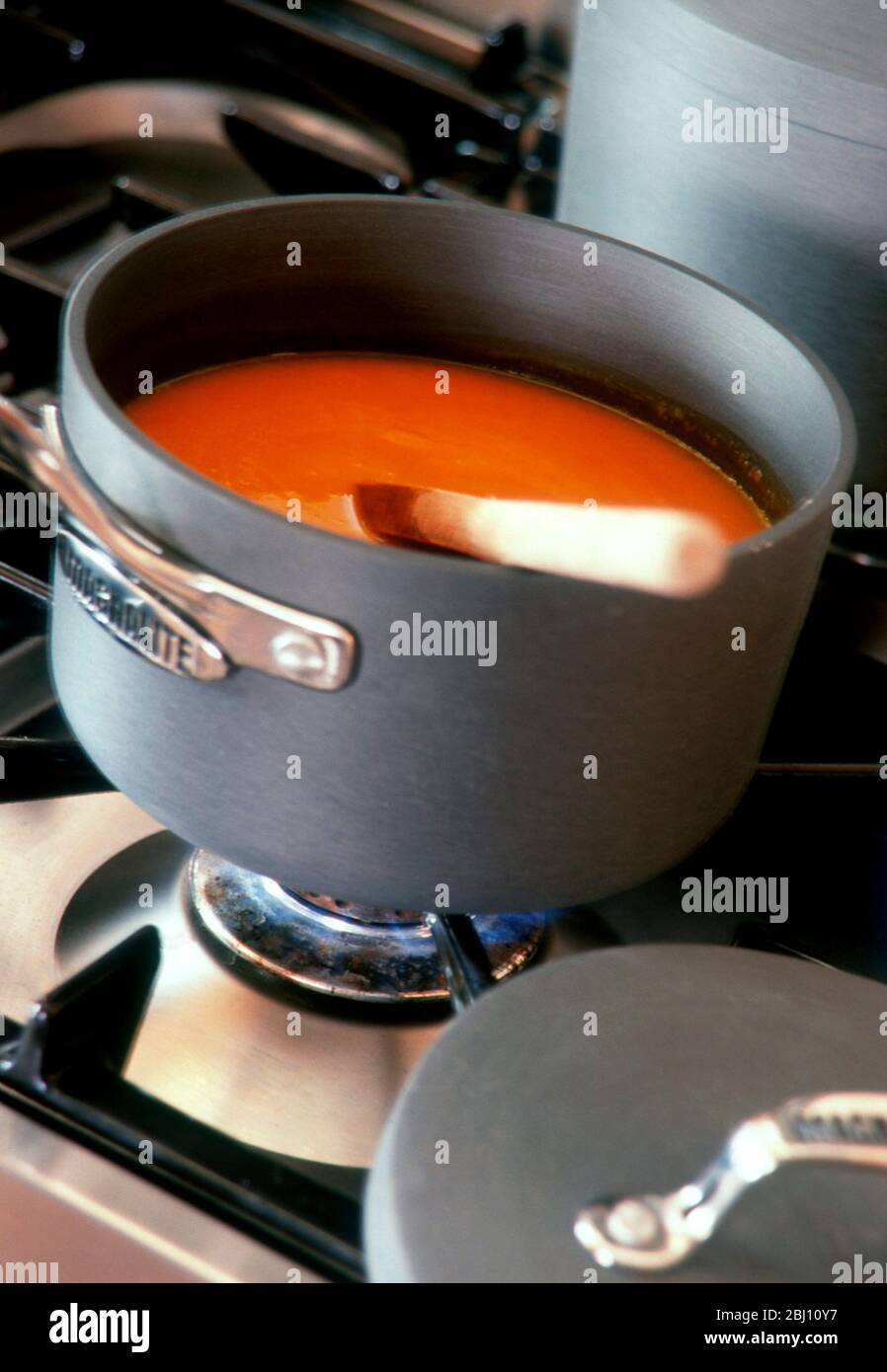 Soupe de tomate chauffée sur la poêle sur le dessus de la cuisinière - Banque D'Images