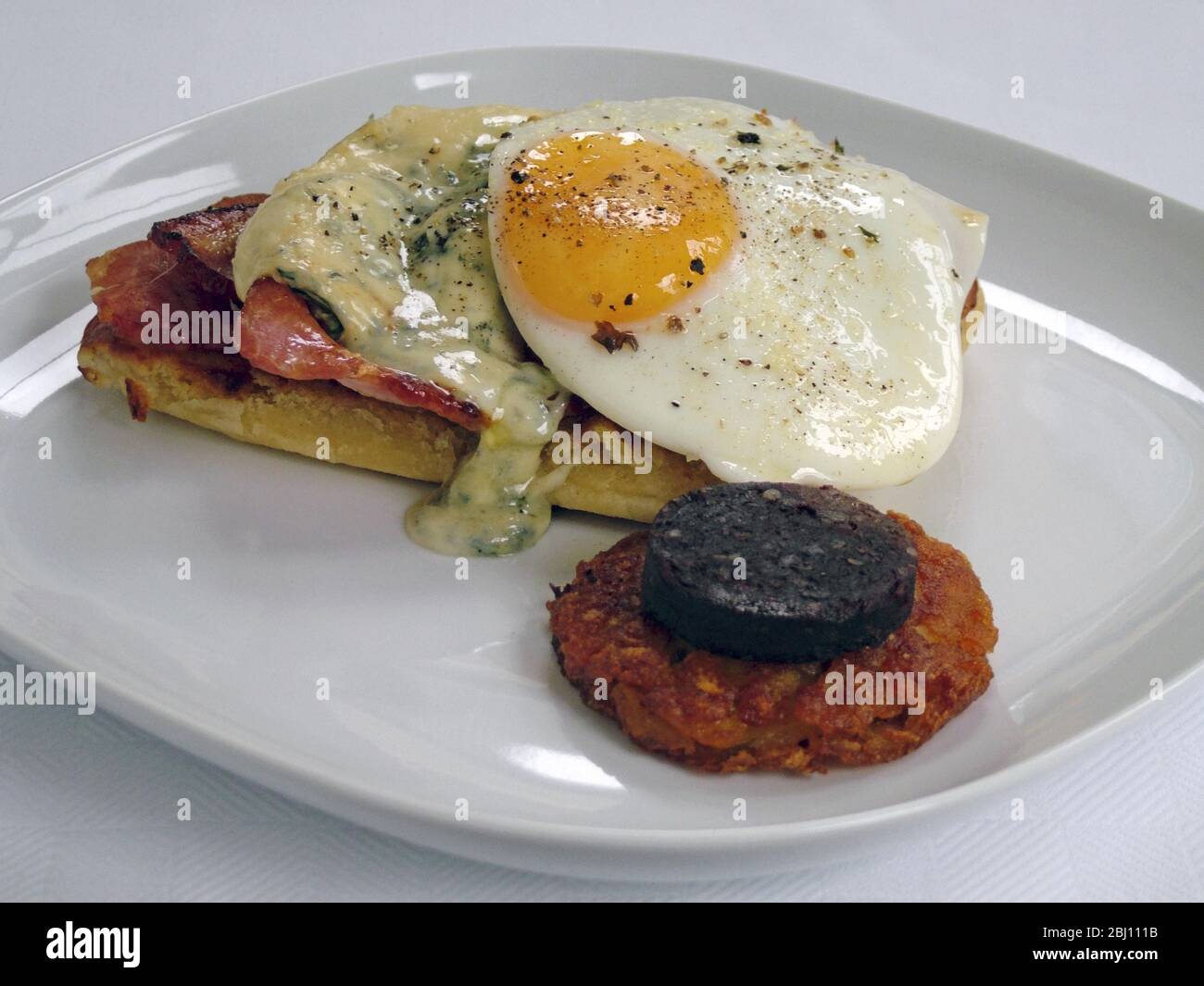 Petit déjeuner anglais complet avec bacon et œufs, gruyère fondue sur toast, pudding noir et pommes de terre sautées Banque D'Images