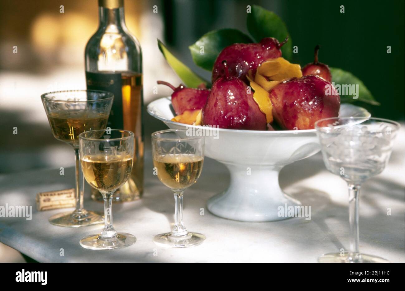 Poires au vin rouge servies à l'extérieur au soleil de printemps français avec vin de dessert - Banque D'Images