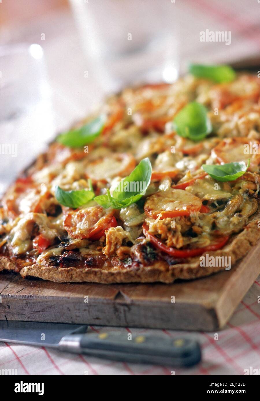 Pizza aux tomates et au fromage sur base complète avec feuilles de basilic - Banque D'Images