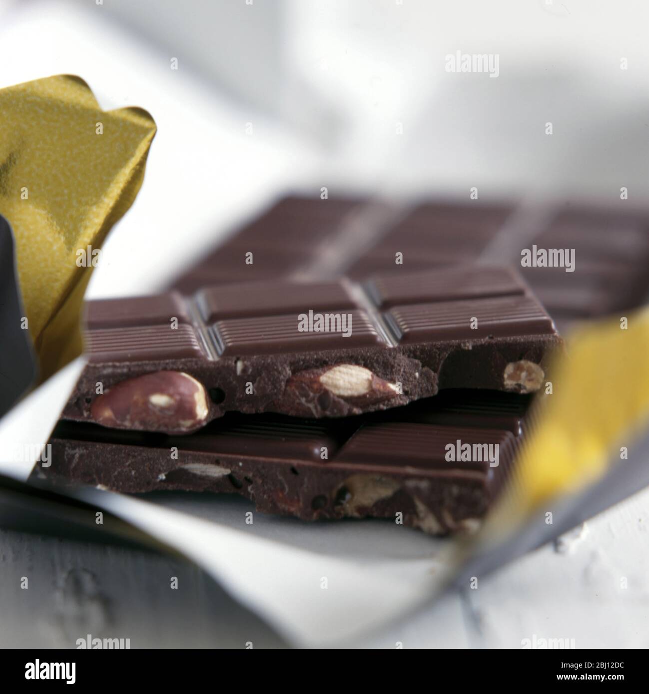 Barre d'amandes en chocolat cassée et assise sur l'emballage - Banque D'Images