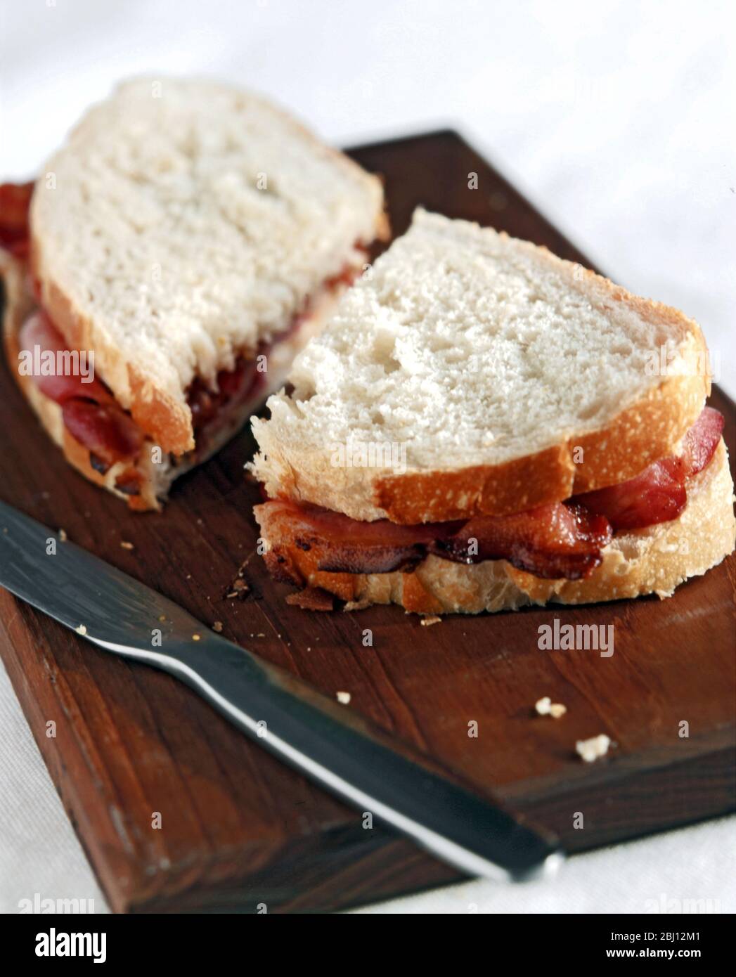 Sandwich au bacon avec pain blanc croustillant à bord avec couteau - Banque D'Images