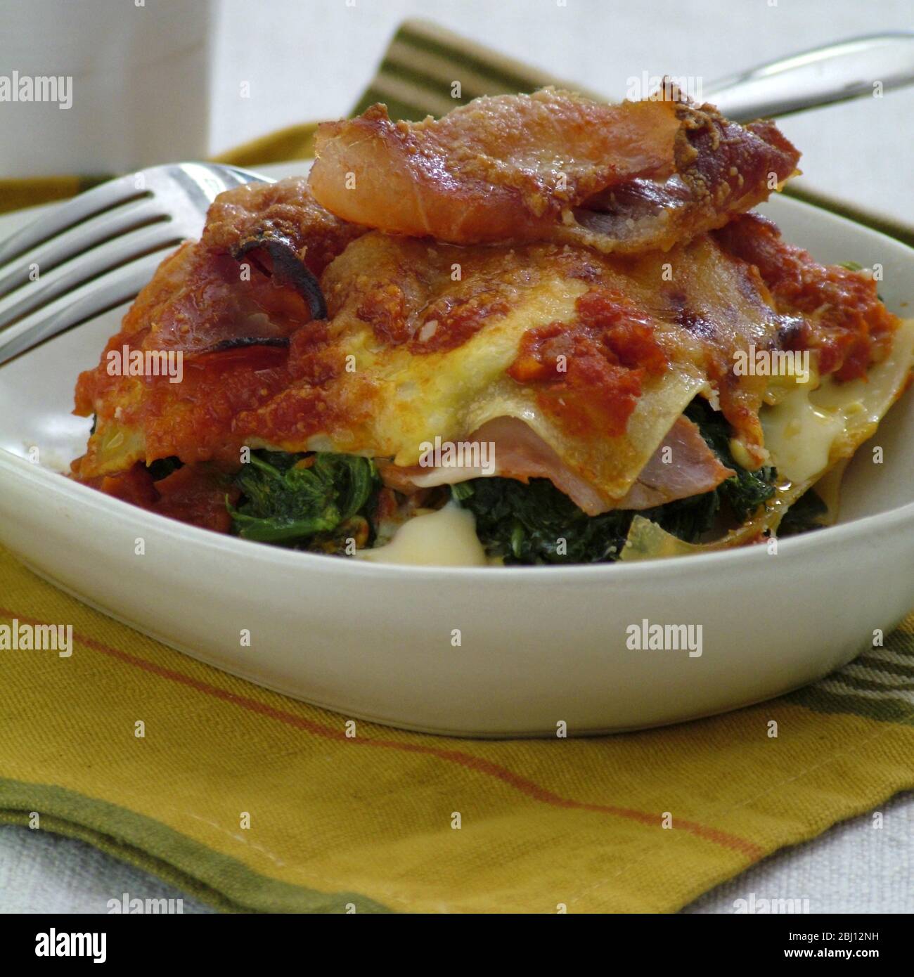Portion de lasagnes avec jambon de parme, épinards et fromage - Banque D'Images